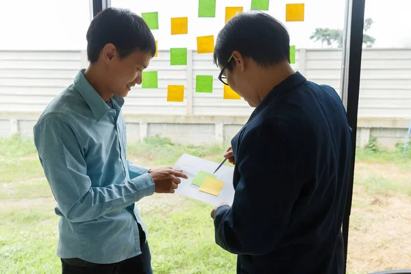 UX or UI designers designing on their smartphone application layout prototype project using digital tablet and sticky notes to share idea.