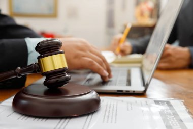 Avukatın ofisindeki masada tahta tokmak var. Avukatın müvekkille takım toplantısı yapması. Hukuk kavramları, tavsiyeler, hukuk hizmetleri.