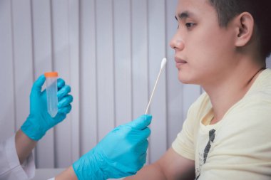 Doktor ya da tıbbi personel laboratuvarda muayene için hastadan salgılar topluyor. Salgın Koronavirüs, COVID-19.