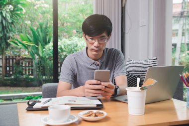 Ofisin bir köşesinde akıllı telefon tutan bir adam..