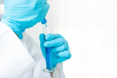 Araştırmacı ya da bilim adamları laboratuardaki test tüpüne sıvı örneği yüklüyorlar. Araştırmacılar COVID-19 virüsünü tedavi etmek için aşı ve ilaç geliştiriyorlar..