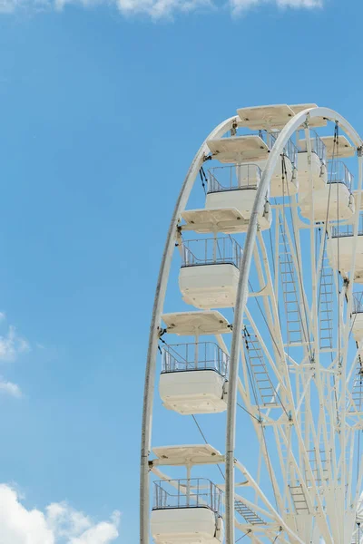 Ferris wheel on the blue cloudy sky. Background concept of happy holidays time. Stock Picture