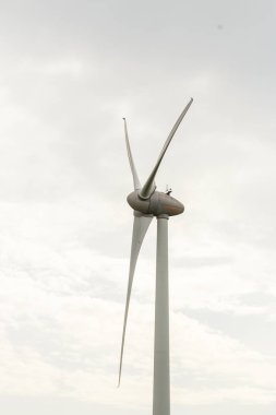Rüzgar türbini bulutlu bir günde dönüyor. Elektrik enerjisi üretimi modern teknoloji. Yenilenebilir enerji kaynakları kavramı. Ekoloji ve çevre dostu enerji üretimi. Yakın çekim