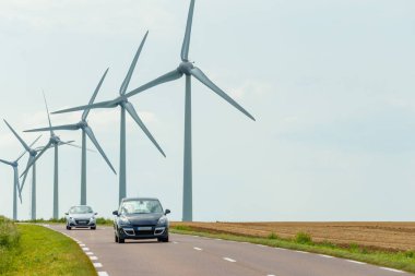 Normandiya, Fransa'da ülke yoluna yakın elektrik üretimi için bir elektrik santralinin rüzgar türbinleri. Kırsal arazi. Çevre dostu elektrik üretimi