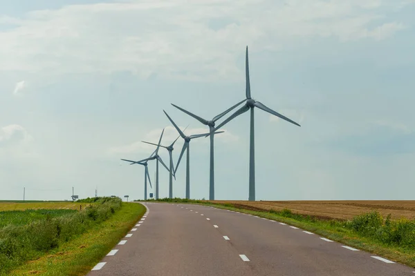 Turbinas eólicas de uma usina para geração de eletricidade perto da estrada rural na Normandia, França. Paisagem rural. Produção de electricidade respeitadora do ambiente — Fotografia de Stock