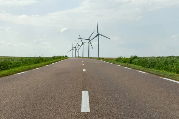 Normandiya, Fransa'da ülke yoluna yakın elektrik üretimi için bir elektrik santralinin rüzgar türbinleri. Kırsal arazi. Çevre dostu elektrik üretimi