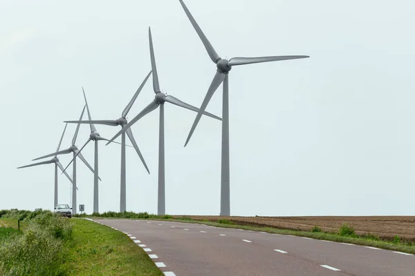 Turbinas eólicas de uma usina para geração de eletricidade perto da estrada rural na Normandia, França. Paisagem rural. Produção de electricidade respeitadora do ambiente — Fotografia de Stock