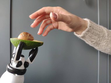 Genç bir kadının el, arka plan veya kavramı bir avokado bir robotun el uzanır.