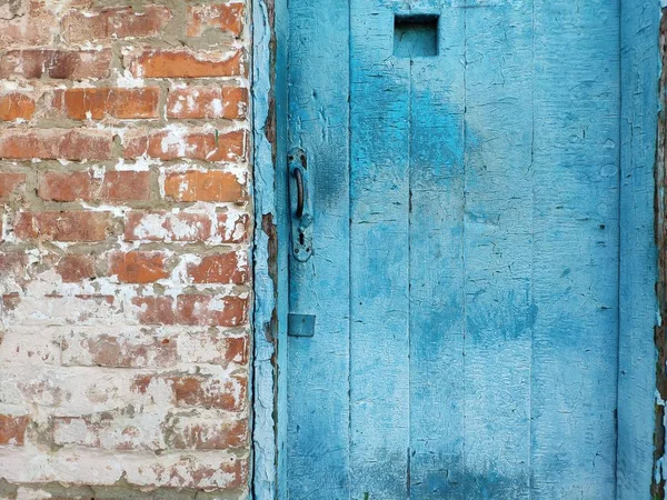 Old wooden door with a metal handle, a piece of brickwork red brick — Stock Photo, Image