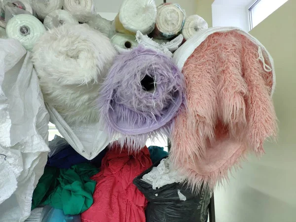 Rolls of fabric and faux fur are on the top shelves in the fabric warehouse