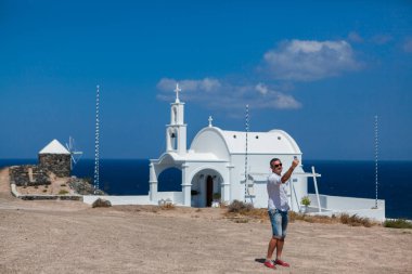 Adam Santorini mimari duruyor ve saatine bakar