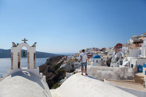 L'uomo si trova in mezzo all'architettura di Santorini e guarda il suo orologio — Foto Stock