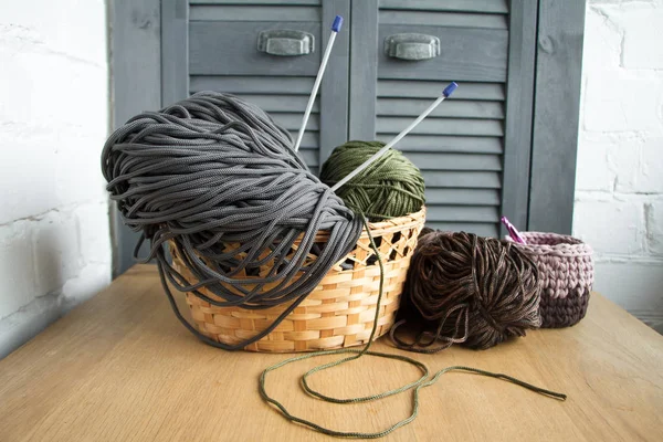 Traditional colorful yarns for hobby knitting in a straw eco basket on a light wooden surface. — Stock Photo, Image