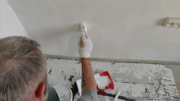 4K Barbe Homme Peinture de murs intérieurs à plat à l'aide d'un pinceau. Beau jeune homme qui fait des réparations - peint activement le mur avec de la peinture blanche . — Video