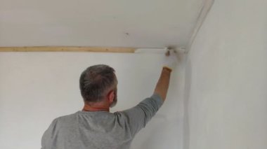 4k sakallı adam boya fırçası kullanarak düz iç duvarlar resim. Yakışıklı genç adam tamir yapıyor-aktif beyaz boya ile duvar boyaları. Ev Renovasyonu veya yeniden dekorasyon konsepti.
