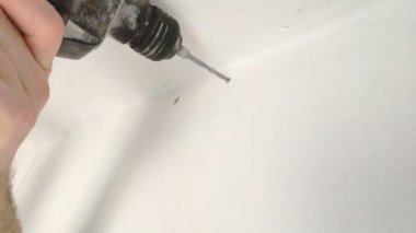 Bir adam matkaplar, matkap, beton, elektrik matkap, eller kapatmak beyaz oda, iç ve ev yenileme elektrik matkap tutun.