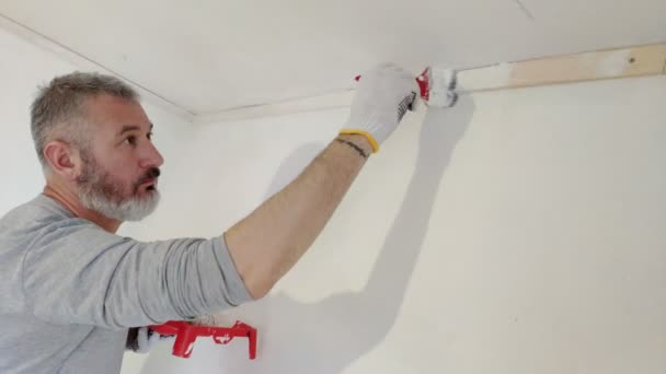 轴承人油漆内部墙壁在平面使用画笔 英俊的年轻人做修理 活跃地油漆墙壁用白色油漆 家居装修或装修概念 — 图库视频影像