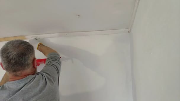轴承人油漆内部墙壁在平面使用画笔 英俊的年轻人做修理 活跃地油漆墙壁用白色油漆 家居装修或装修概念 — 图库视频影像