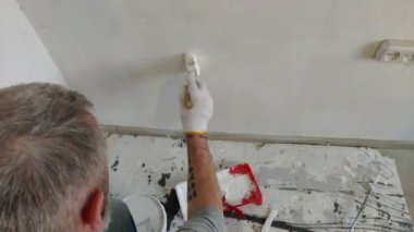 4k sakallı adam boya fırçası kullanarak düz iç duvarlar resim. Yakışıklı genç adam tamir yapıyor-aktif beyaz boya ile duvar boyaları. Ev Renovasyonu veya yeniden dekorasyon konsepti.