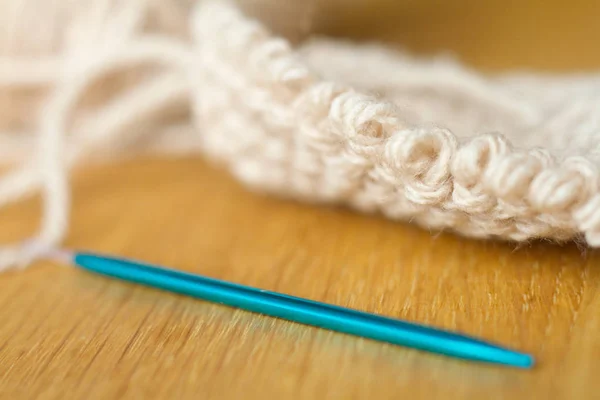 Extremamente close-up tricô de fios bege, agulha, ganchos de crochê. Trabalhe em um novo produto. Foco suave seletivo . — Fotografia de Stock