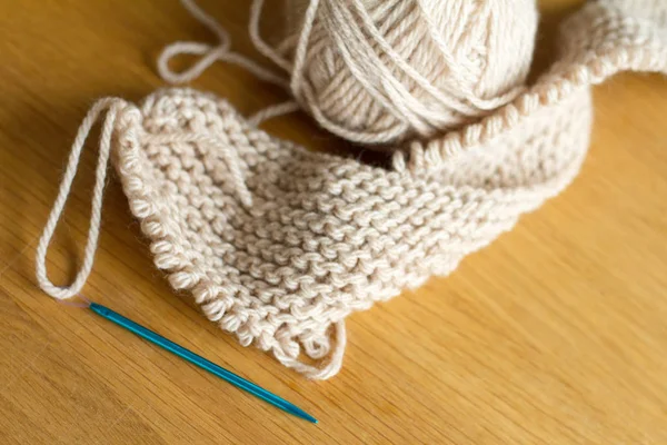 Extremely close-up knitting from beige yarn, needle, crochet hooks. Work on a new product. Selective soft focus. — Stock Photo, Image
