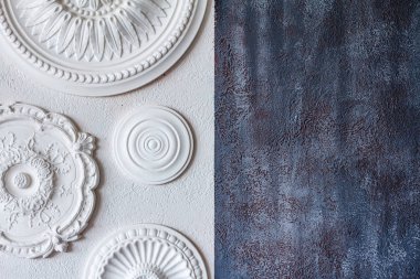 A two-color background, gray decorative plaster and a white wall with several white ceiling rosettes