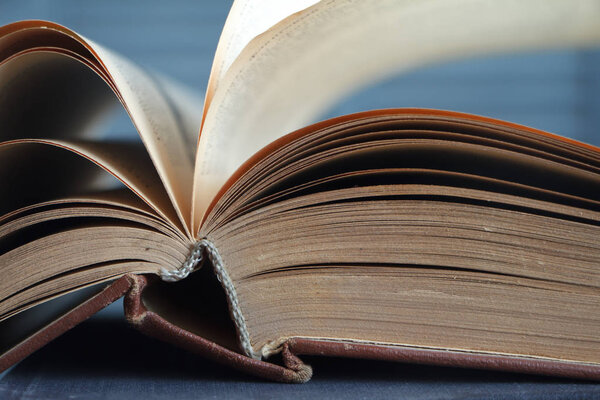 Extreme close-up of an open book on a wooden surface against the background of a gray wall, the concept of education and training.