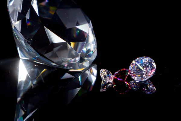 Huge diamond and several chic crystals on a deep black mirror surface, shimmer and sparkle — Stock Photo, Image