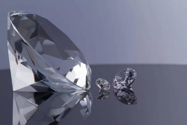 Diamante enorme e diversi cristalli chic su una superficie dello specchio nero e sfondo bianco, luccichio e scintilla — Foto Stock