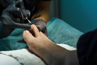 Güzellik uzmanı güzellik salonunda bir pedikür için tırnak çubuğu öğütür.