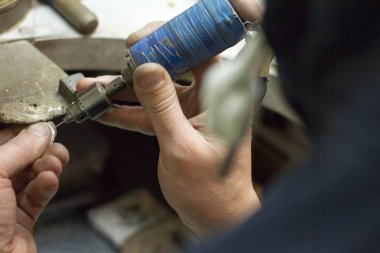 Usta kuyumcu elinde çalışma aracı tutar ve işyerinde mücevher yapar