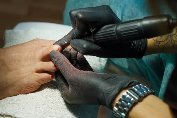 Esteticista muele la barra de uñas para una pedicura en el salón de belleza . — Foto de Stock