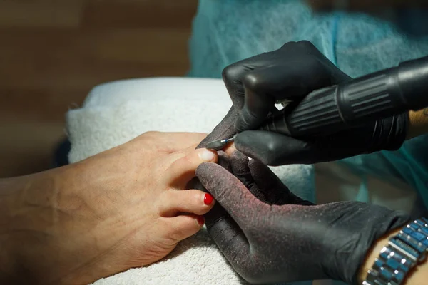 Kosmetikerin schleift Nagelbalken für Pediküre im Schönheitssalon. — Stockfoto