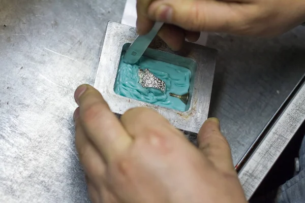 The master jeweler holds the working tool in his hands and makes jewelery at his workplace
