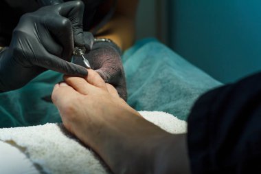 Güzellik uzmanı güzellik salonunda bir pedikür için tırnak çubuğu öğütür.