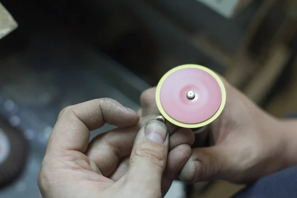 The master jeweler holds the working tool in his hands and makes jewelery at his workplace