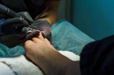 Güzellik uzmanı güzellik salonunda bir pedikür için tırnak çubuğu öğütür.