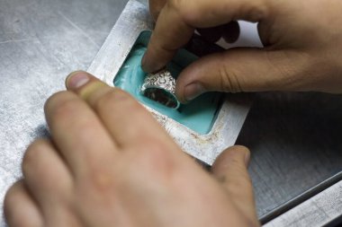 Usta kuyumcu elinde çalışma aracı tutar ve işyerinde mücevher yapar