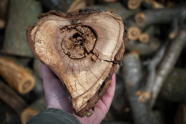 Fechar as mãos masculinas segurando um corte de madeira em forma de coração para aquecer uma casa, fundo ou conceito — Fotografia de Stock