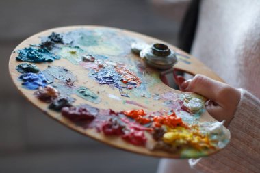 Bir yağlı boya oluşturma bir spatula ile bir palet üzerinde boyakarıştırma kadın elleri yakın çekim