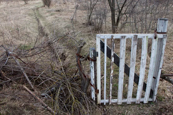 Stará bílá brána zavírá vchod po polní cestě, dvě stopy v terénu. — Stock fotografie