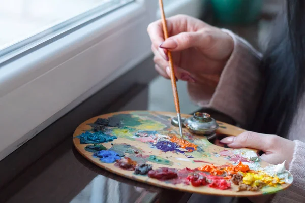 Close-up of female hands mixing paints on a palette with a spatula creating an oil painting — Stock Photo, Image