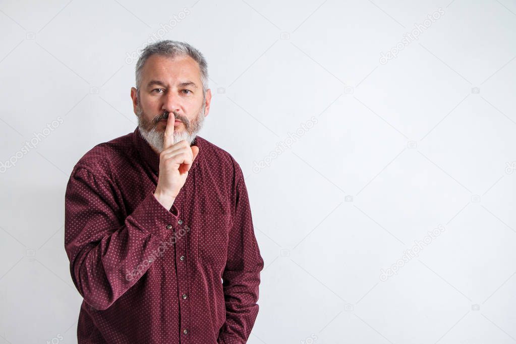 gray bearded man have the finger on lips as man gesturing shh sign, please be silent concept