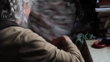 Eski şeyleri karıştıran gri saçlı yaşlı bir kadın, eski evindeki yatağı temizler, yalnız yaşar, seçici odaklar.