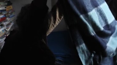 Eski şeyleri karıştıran gri saçlı yaşlı bir kadın, eski evindeki yatağı temizler, yalnız yaşar, seçici odaklar.