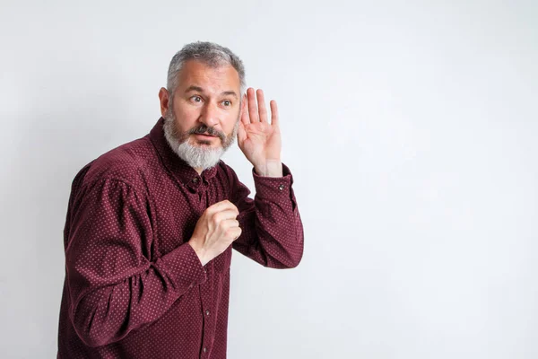 Man skäggiga hipster hålla handen nära örat för att höra bättre, avlyssning och spyingblems. — Stockfoto