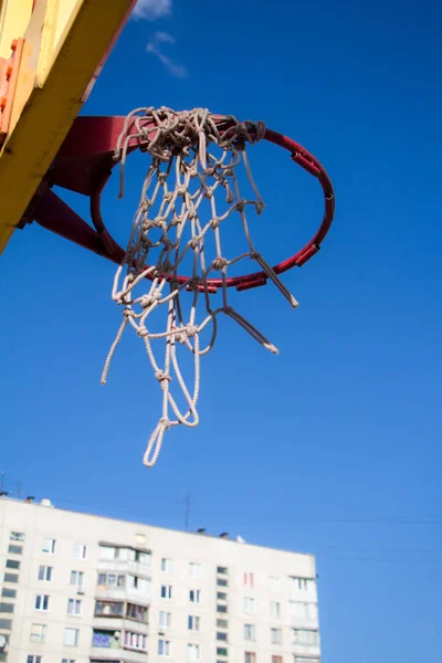 澄んだ青空とモダンな建物の上に古いバスケットボールフープのクローズアップ底面図 — ストック写真