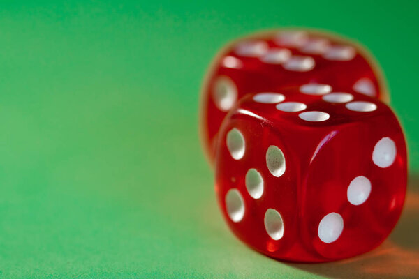 Крупный план двух красных костей с выигрышным номером на верхней стороне на зеленой поверхности
