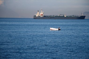 Tanınmaz adam denizde küreklerle bir teknede yelken, büyük bir liner üzerinde bir teknede bir balıkçı
