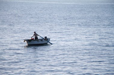 Denizde küreklerle bir teknede yelken tanınmayan adam, bir teknede bir balıkçı
